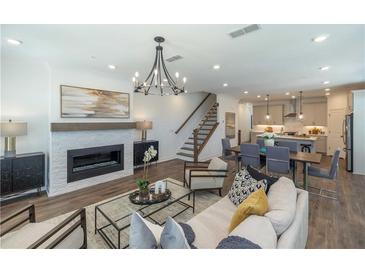 Bright, open-concept living space with modern chandelier, sleek fireplace, and seamless flow to dining and kitchen areas at 1007 Crown Oak St # 45, Johns Creek, GA 30022