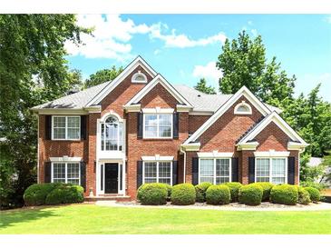 Stunning two-story red brick home featuring manicured lawn and lush landscaping at 194 Lake Ruby Dr, Suwanee, GA 30024