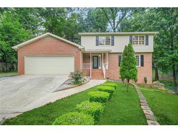 Charming two-story brick home featuring a well-manicured lawn and inviting front porch at 574 Hickory Hills Ct, Stone Mountain, GA 30083