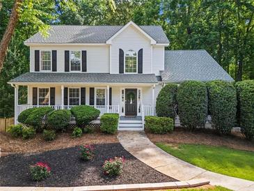 Charming two-story home boasts a well-manicured lawn, lush landscaping, and a welcoming front porch with black shutters at 6065 Ashbury Ln, Cumming, GA 30028
