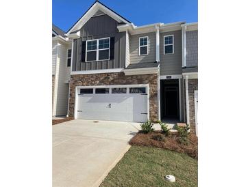 Charming townhome showcasing a two-car garage, stone accents, and neutral gray siding at 1404 Gray Branch Dr, Lawrenceville, GA 30045