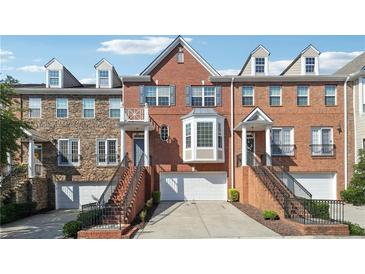 Brick townhome with attached garages, symmetrical window placement, and well-maintained landscaping at 6043 China Rose Lane, Johns Creek, GA 30097