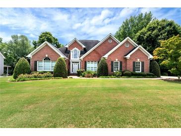 Charming brick home boasts a manicured lawn, lush landscaping, and classic architectural details at 3885 Lake Juliette Dr, Buford, GA 30519