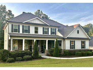 Stunning two-story home with beautiful landscaping and a welcoming covered front porch with stone accents at 140 Discovery Lake Dr, Fayetteville, GA 30215