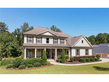 Charming two-story home featuring a welcoming front porch and a beautifully landscaped front yard under a clear blue sky at 140 Discovery Lake Dr, Fayetteville, GA 30215