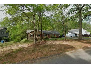 Charming one-story home featuring brick facade, red shutters and mature trees in a leafy green neighborhood at 165 Wellington Dr, Mcdonough, GA 30252