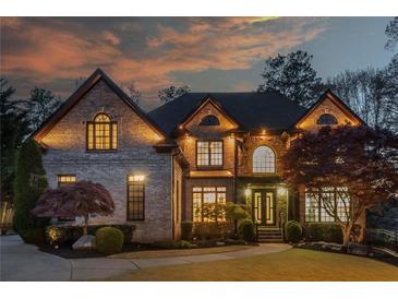 Elegant two-story home with manicured lawn, stone facade, and detailed trim is beautifully lit at twilight at 2461 Oak Grove Ne Ests, Atlanta, GA 30345