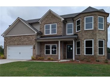 Charming two-story brick home with a well-manicured lawn and attached two-car garage at 596 Rodeo Dr, Auburn, GA 30011