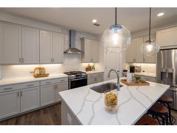 Stylish kitchen features an island with seating, grey cabinets, and stainless steel appliances at 1003 Crown Oak St # 43, Johns Creek, GA 30022