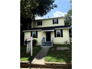 Charming two-story home features a symmetrical design, light yellow siding, and a welcoming entrance at 210 Ormond Sw St, Atlanta, GA 30315