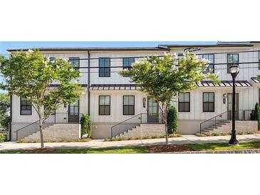 Charming townhome showcases clean white facade, contrasted by modern black window frames and updated landscaping at 988 Viney Nw Way, Atlanta, GA 30318