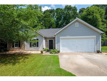 Charming single-story home featuring gray siding, stone accents, manicured lawn, and attached two-car garage at 784 Crestworth Xing, Powder Springs, GA 30127