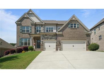 Beautiful brick two-story home with a manicured lawn and a two-car garage at 4154 Hawking Dr, Suwanee, GA 30024