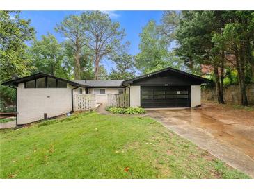 Charming ranch-style home with a well-manicured lawn, white brick, a black roof, and a two-car garage at 3068 Cherry Blossom Ln, Atlanta, GA 30344