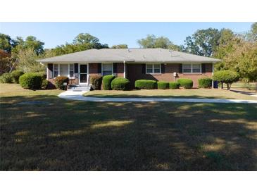 Charming brick home featuring a well-manicured lawn and mature landscaping with decorative bushes at 893 Andrews Dr, Conyers, GA 30012