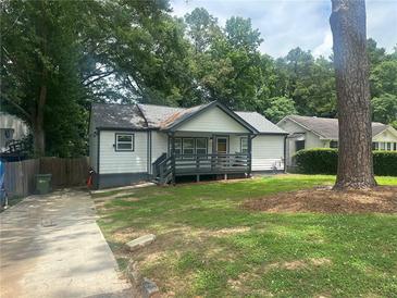 Charming single-story home with a covered front porch, lush green lawn, and mature trees providing shade at 2225 Baker Nw Ter, Atlanta, GA 30318