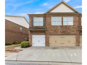 Stone-clad townhouse exterior featuring a two-car garage and meticulously maintained landscaping at 805 Pleasant Hill Nw Rd # 231, Lilburn, GA 30047