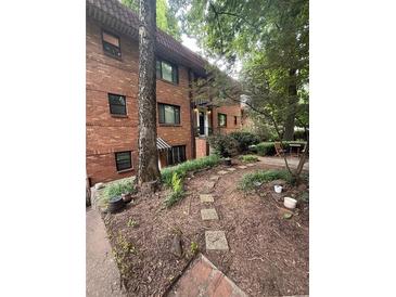 Charming brick exterior of a multi-story condo with landscaped front yard and stepping stone path at 314 3Rd Ne St # 4, Atlanta, GA 30308