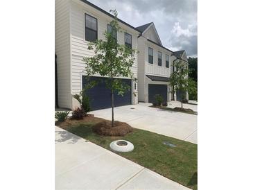 Modern townhome with white siding, a dark garage door, and landscaping at 2853 Bullfrog Ln # 172, Gainesville, GA 30115