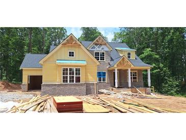 New two-story home with yellow siding, gray brick, and an attached garage in a wooded neighborhood at 4545 Greyson Manor Dr, Cumming, GA 30041