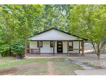 Charming cottage-style home with a cozy front porch and a well-maintained lawn surrounded by lush trees at 2155 Cove Trl, Cumming, GA 30041