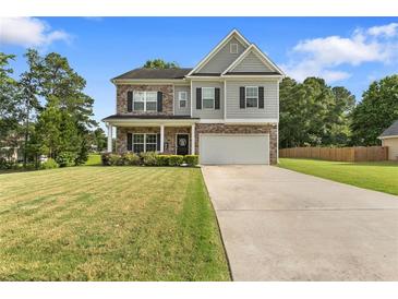 Charming two-story home with stone accents, a well-manicured lawn, and a welcoming two-car garage at 140 Canyons Ct, Hampton, GA 30228