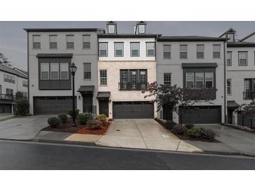 Modern townhome featuring light brick, a one-car garage, and manicured landscaping at 1505 Slopeside Loop, Smyrna, GA 30082