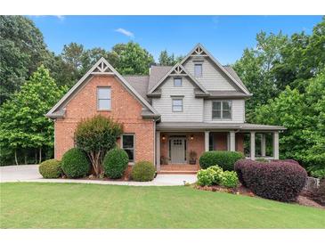 Charming two-story home with a brick and gray shingle exterior, complemented by a lush, well-manicured front yard at 7535 Antique Barn Ave, Cumming, GA 30041