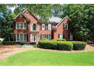 Charming brick home featuring manicured landscaping and a welcoming front lawn at 1558 Amberwood Creek Nw Dr, Kennesaw, GA 30152