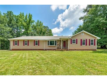 Inviting ranch-style home featuring a large lawn, complemented by charming red window shutters at 35 Brookside Ct, Villa Rica, GA 30180