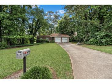 Charming single-story home with a two-car garage and a long driveway surrounded by lush greenery at 2935 Sawgrass Sw Trl, Lilburn, GA 30047