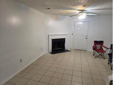Living room with tile flooring, fireplace and ceiling fan with attached door at 437 Saint Ives Sq, Stone Mountain, GA 30083