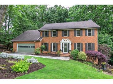 Charming two-story brick home with a well-manicured lawn and mature trees at 425 Bellflower Ct, Roswell, GA 30076