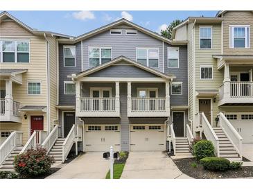 Charming townhome with two-story porch, attached garages, and well-maintained landscaping, creating inviting curb appeal at 1536 Liberty Nw Pkwy, Atlanta, GA 30318