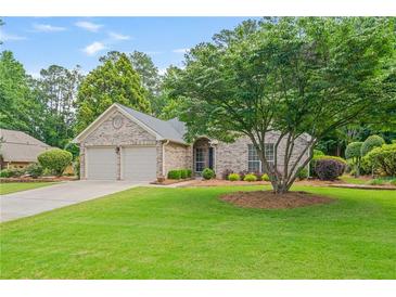 Charming brick home with a well-manicured lawn and a mature shade tree at 425 Greenmont Walk Ct, Alpharetta, GA 30009