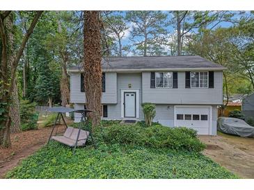 Charming home featuring a well-kept lawn, classic siding, and an attached garage, perfect for suburban living at 1377 Tucker Woods Dr, Norcross, GA 30093