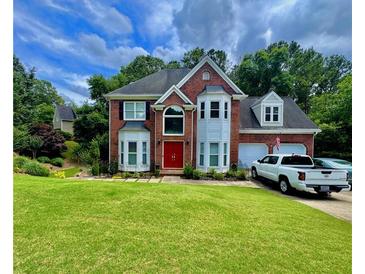 Charming two-story brick home with a well-manicured lawn and attached two-car garage at 703 Overlook Point, Woodstock, GA 30189