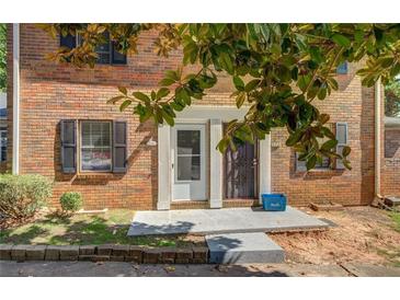 Charming brick townhome featuring a cozy front porch entrance and lush green foliage at 115 Plantation Dr, Clarkston, GA 30021