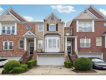 Attractive brick townhome with a two-car garage, manicured bushes, and a well-kept lawn at 1286 Creekside Se Ter, Smyrna, GA 30082