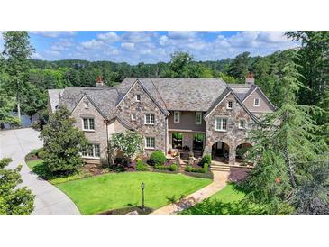 Stunning stone-and-brick home featuring a manicured lawn and a stone walkway leading to an arched front entrance at 4745 Cuyahoga Cv, Suwanee, GA 30024