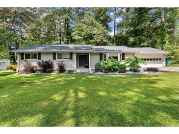 Charming one-story home with a manicured lawn, grey siding, and mature landscaping at 1467 Hewatt Rd, Lilburn, GA 30047