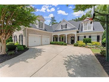 Traditional brick home with a manicured lawn, two-car garage, and charming covered front porch at 956 Kinghorn Nw Dr, Kennesaw, GA 30152