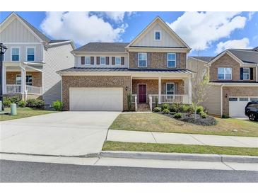 Charming two-story brick home featuring a well-manicured lawn, two car garage, and inviting front porch at 4349 Northmark Ln, Buford, GA 30518
