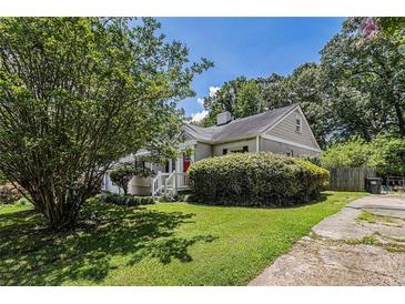 Charming home with a well-maintained lawn and lush greenery, and a bright red front door at 1932 Neely Ave, Atlanta, GA 30344