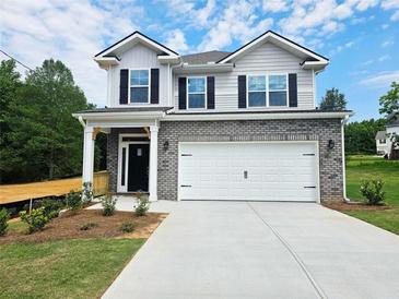 Charming two-story home featuring brick accents, a two-car garage, and a welcoming covered porch at 145 Scarlett Place Dr, Bowdon, GA 30108