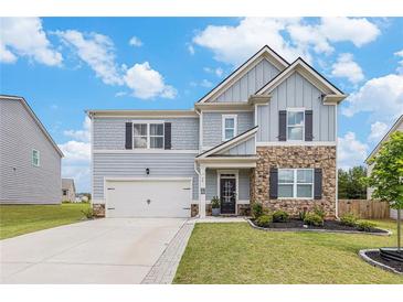 Charming two-story home featuring a stone facade, inviting front porch, well-maintained lawn, and attached two car garage at 36 Ivy Chase Loop, Dallas, GA 30157