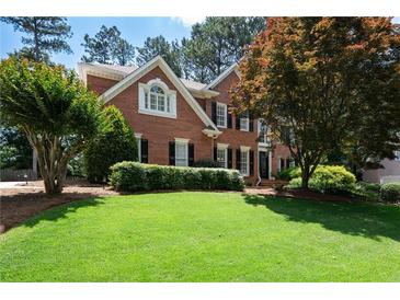Beautiful two-story brick home featuring a well-manicured lawn and mature trees at 410 Beechwood Ln, Woodstock, GA 30189