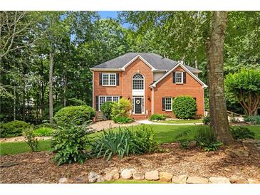 Charming two-story brick home with a well-manicured lawn and mature trees at 6435 Ivey Creek Cir, Cumming, GA 30040