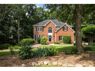 Charming two-story brick home with lush landscaping and mature trees at 6435 Ivey Creek Cir, Cumming, GA 30040