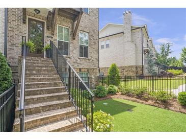 Inviting brick townhouse with landscaped front yard and stairway leading to the main entrance at 134 Everley Walk, Alpharetta, GA 30009